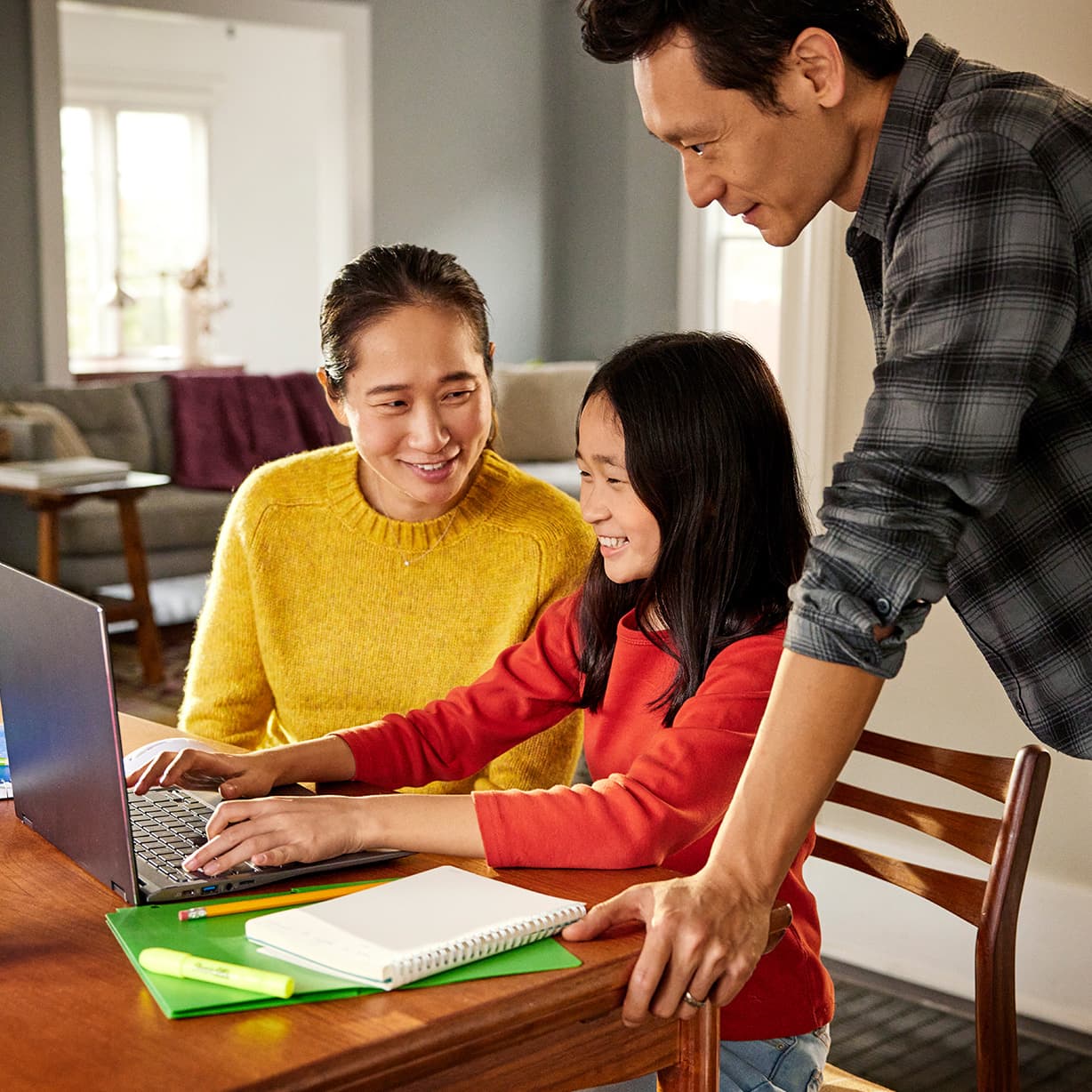 Overhead shot of a father and daughter, both with Chromebooks, seated next to each other on a couch.
